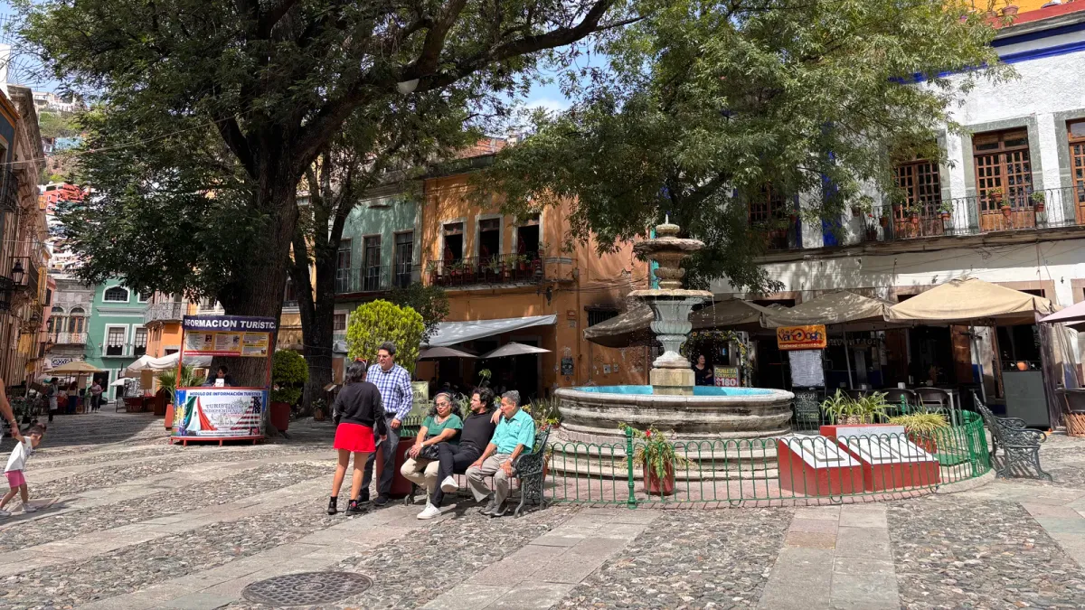 A shaded plaza with a stone fountain and colorful colonial houses in Guanajuato
